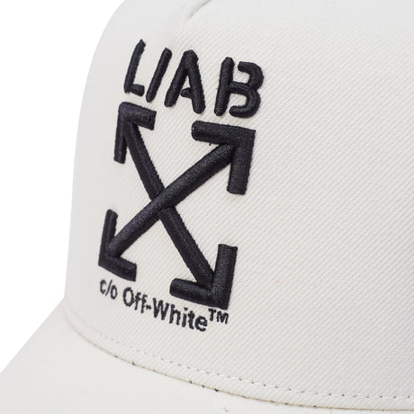 Close-up of a white Off-White cap featuring the black embroidered 'LIAB' logo and crossed arrows symbol with 'c/o Off-White' text on the front panel.