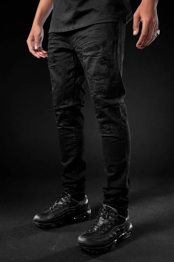 Person wearing black pants and black shoes on a dark background