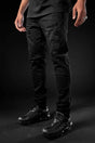 Person wearing black pants and black shoes on a dark background
